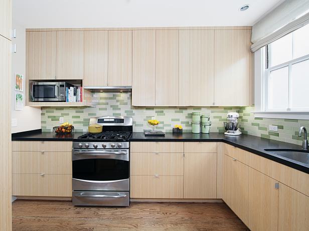 Full kitchen with laminate cabinets and green backdrop tiles.