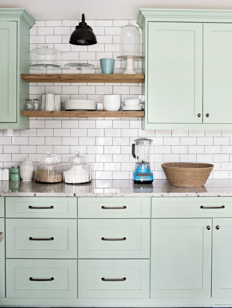 Kitchen with mint green cabinets and white backdrop tiles.