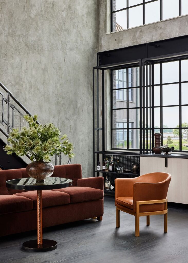Industrial Style Interior Design - A concrete finish wall with a black metal structure across a high-ceiling space, exuding an industrial rustic look.