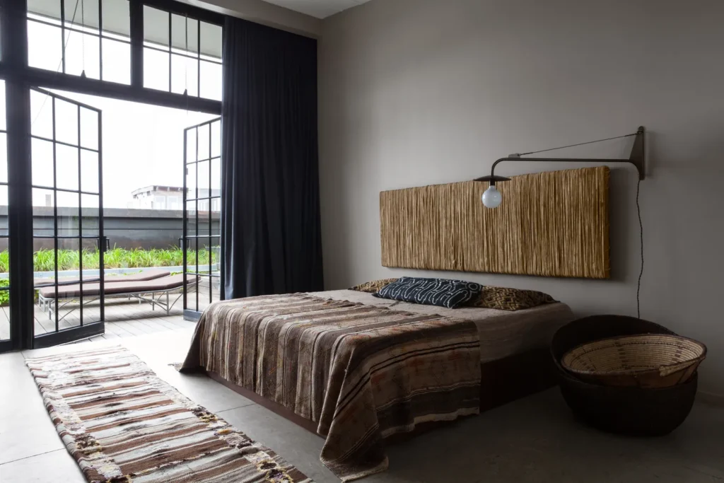 Earthy-toned bedroom with expansive industrial-style door and windows—a perfect industrial style interior.