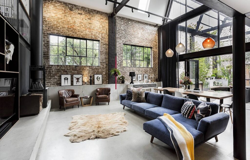 Showcasing an exposed brick accent wall with a black metal frame structure across the living room exuding an industrial rustic look.